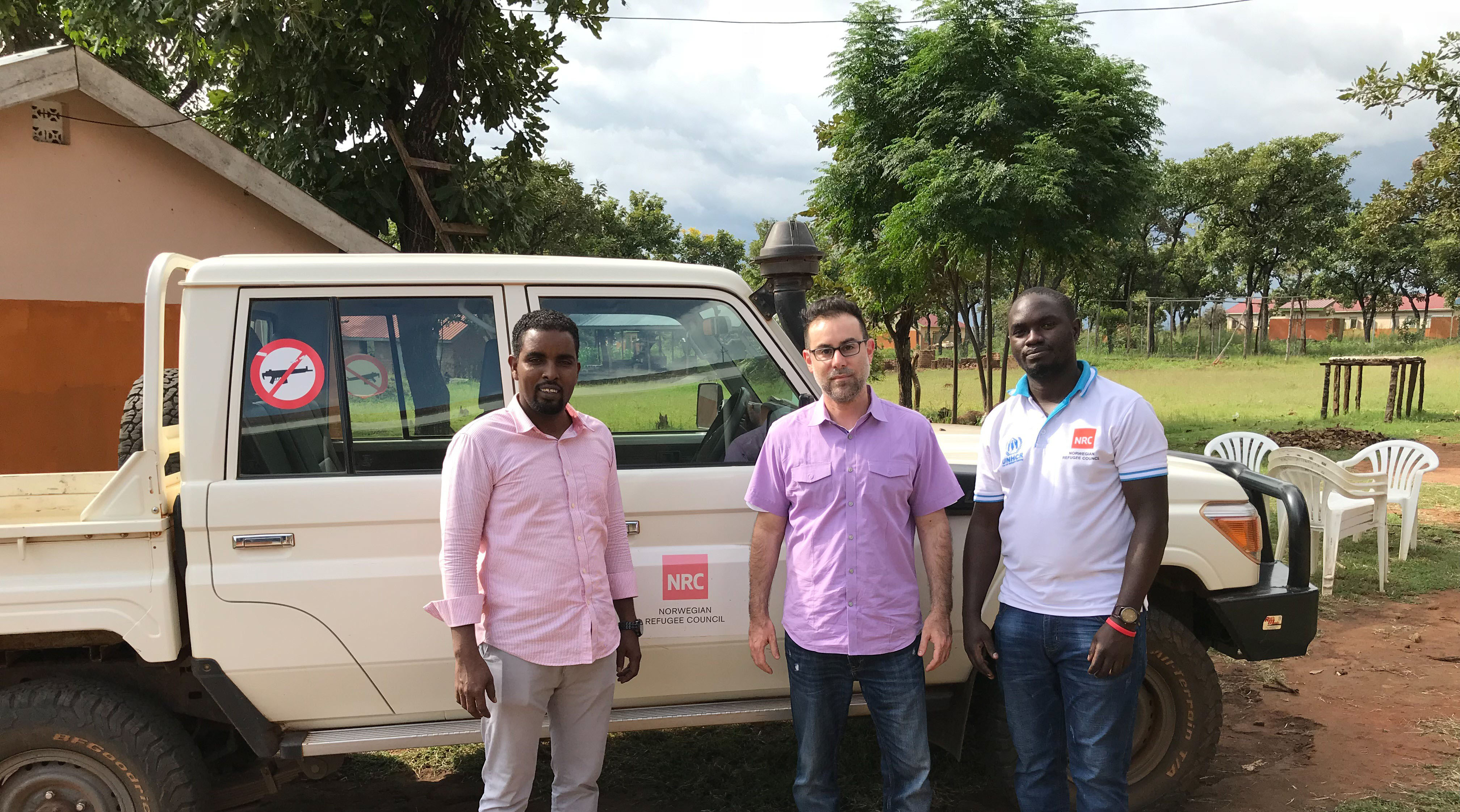 Three men standing in front of a vehicle